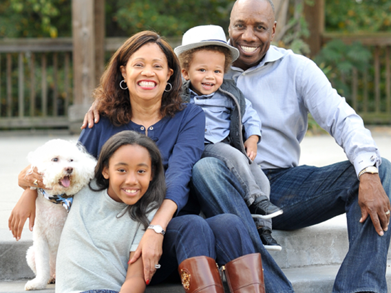 A smiling African-American family and a small dog