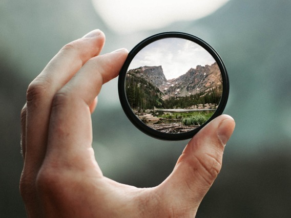 Hand holding a magnifying glass to show the mountains