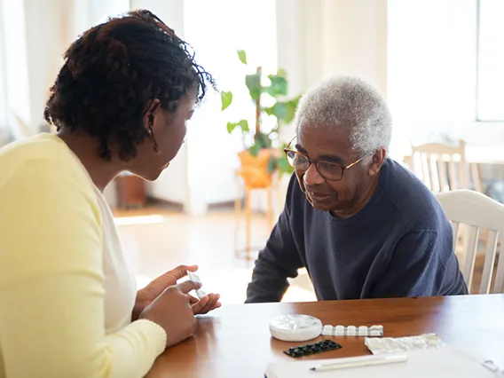 A woman helping an elderly woman with her medication