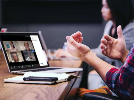 A mans hands in front of a laptop featuring a group chat