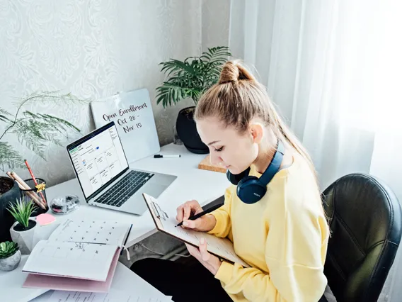 Young woman student near laptop with open enrollment webpage open at home.