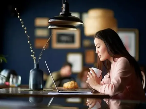 A women at a coffee shop looking at her computer.