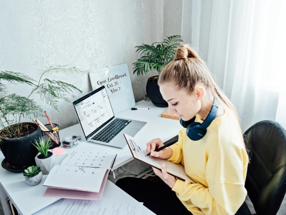 Young woman student near laptop with open enrollment webpage open at home.