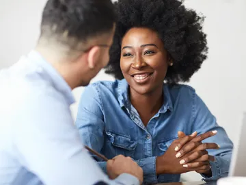 A smiling African-American woman talking to a man.