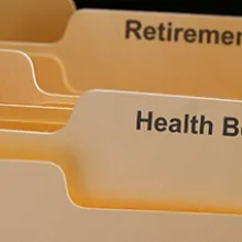 Employee benefits folders labeled health benefits, insurance, retirement