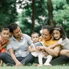 A family of 5 sitting outside on the grass together